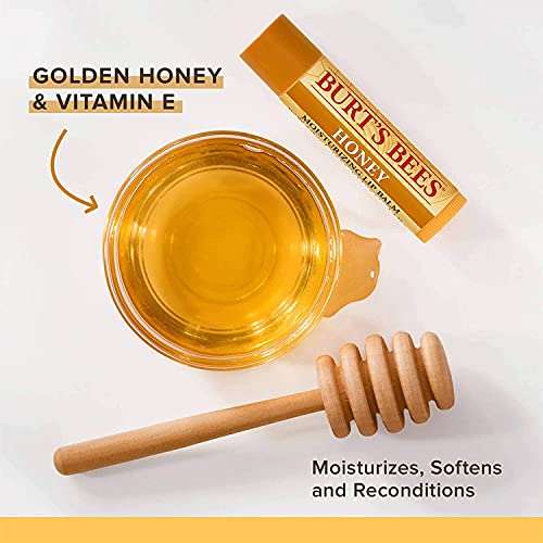 Burt's Bees Honey Lip Balm tube with a golden yellow label, beside amber honey and a wooden honey dipper