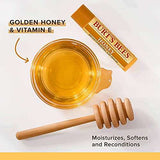 Burt's Bees Honey Lip Balm tube with a golden yellow label, beside amber honey and a wooden honey dipper