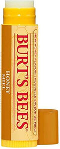 Burt's Bees Honey Lip Balm tube in yellow-orange packaging beside honeycomb and green leaves, with peppermint oil text