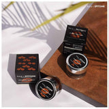 Chocolate Lip Scrub in a black jar and matching box, with orange lip graphics and white lettering on the labels.